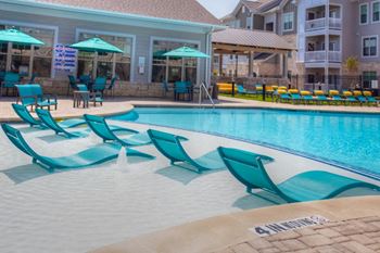 Resort-style pool with tanning shelf and chaise lounges
